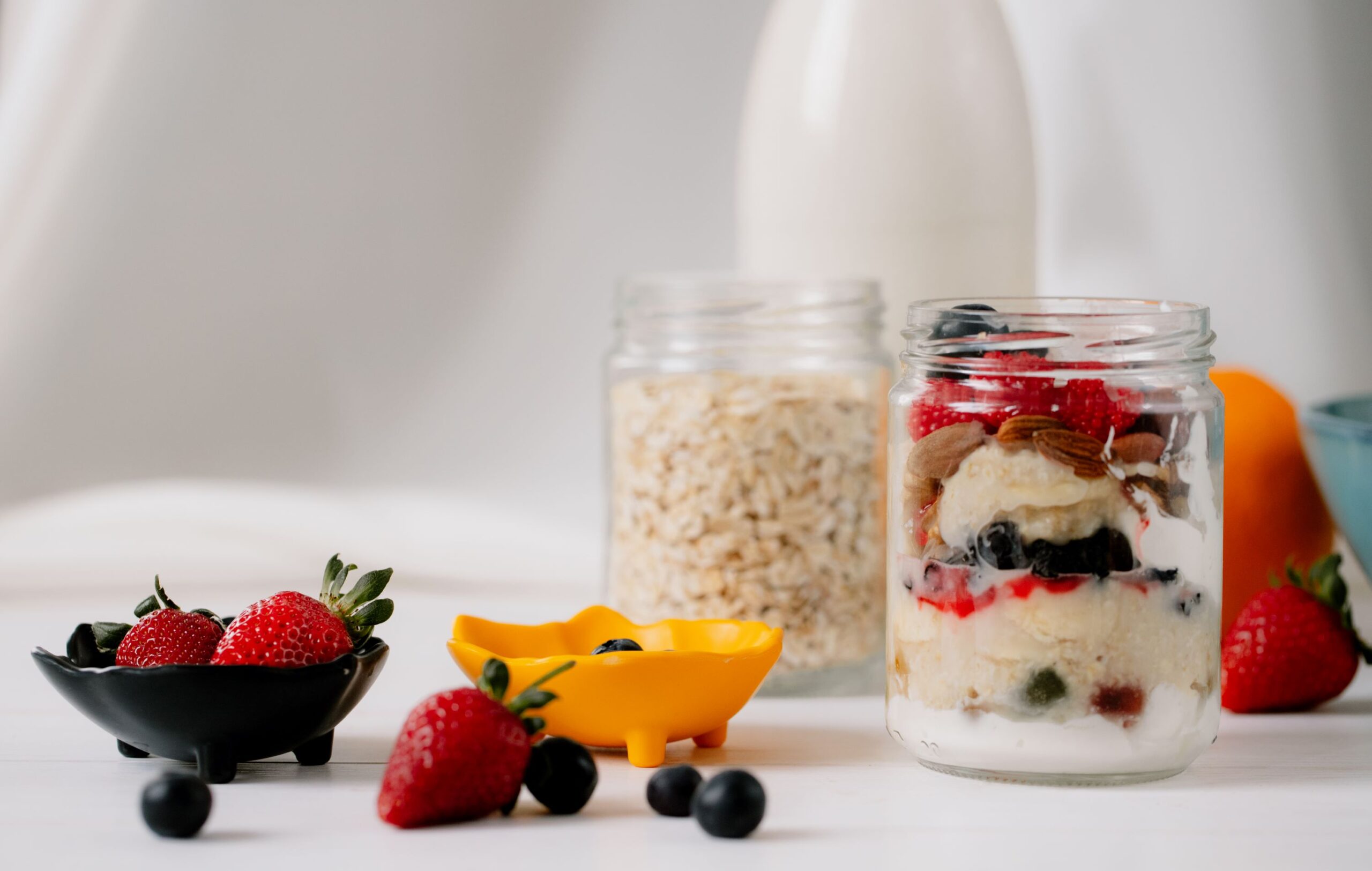 side view overnight oats with fresh strawberries blueberries nuts glass jar rustic table scaled
